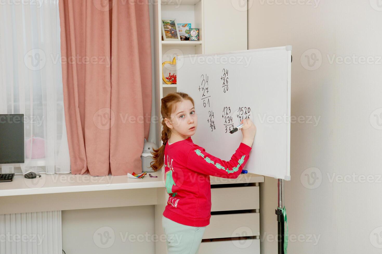 back to school, girl learning to solve examples in a column on the board photo