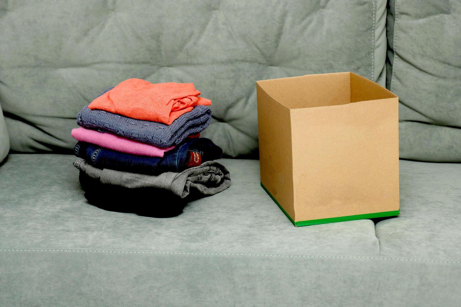 folded clothes next to an empty box on the sofa photo