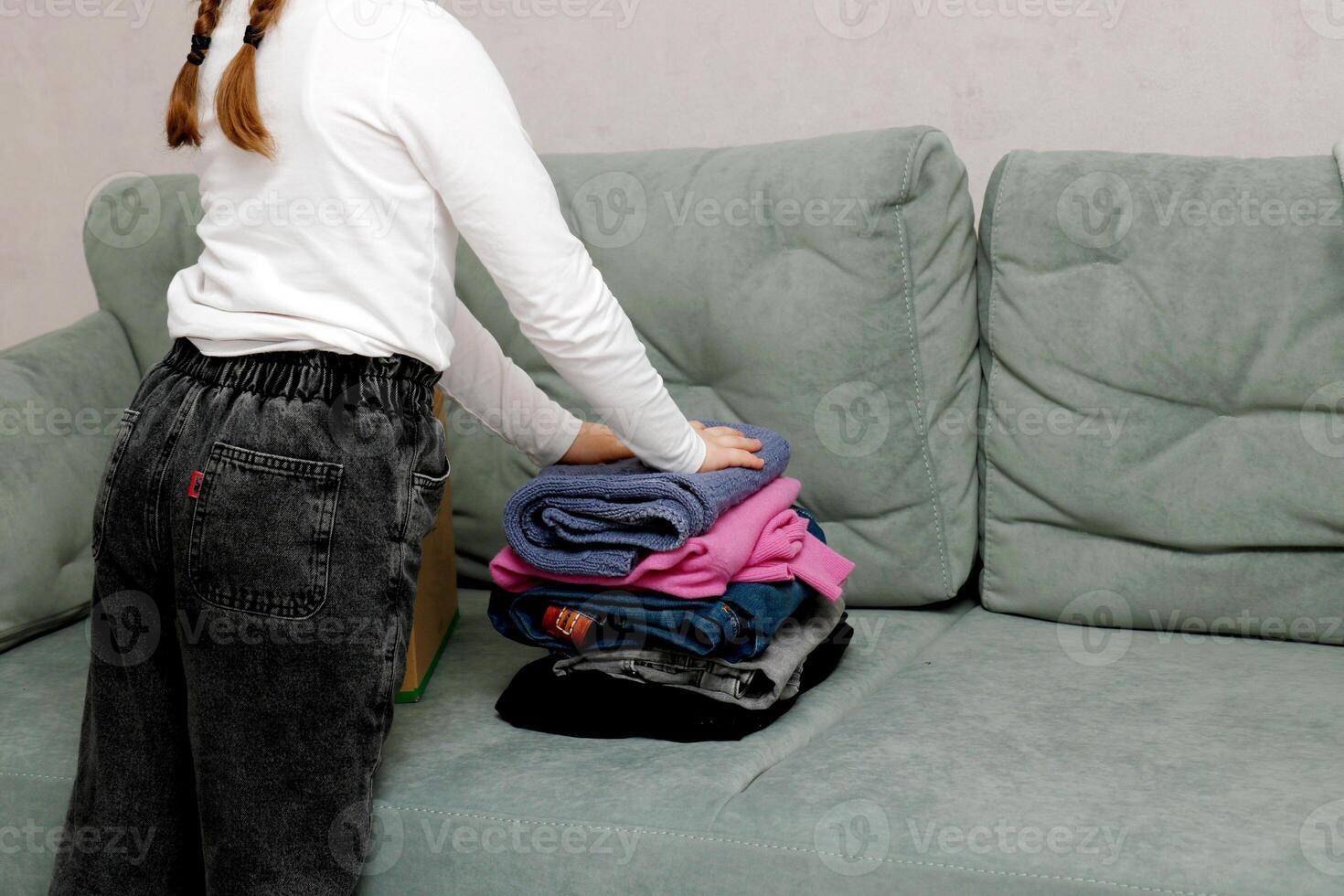 niña con coletas plegable ropa para donación foto
