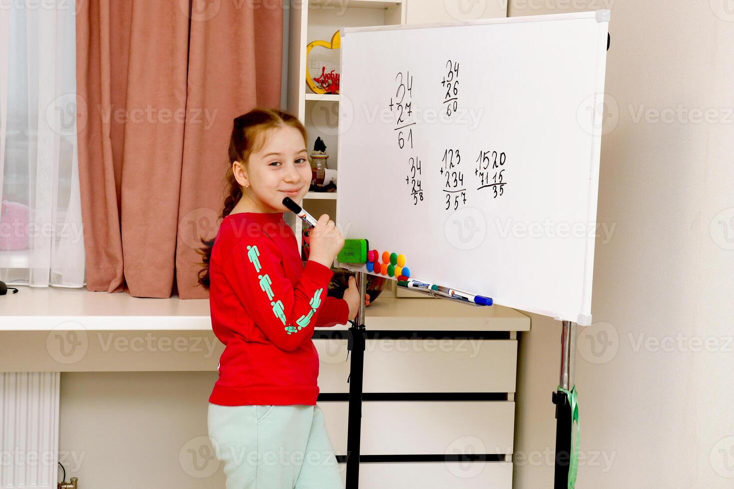 back to school, girl learning to solve examples in a column on the board photo