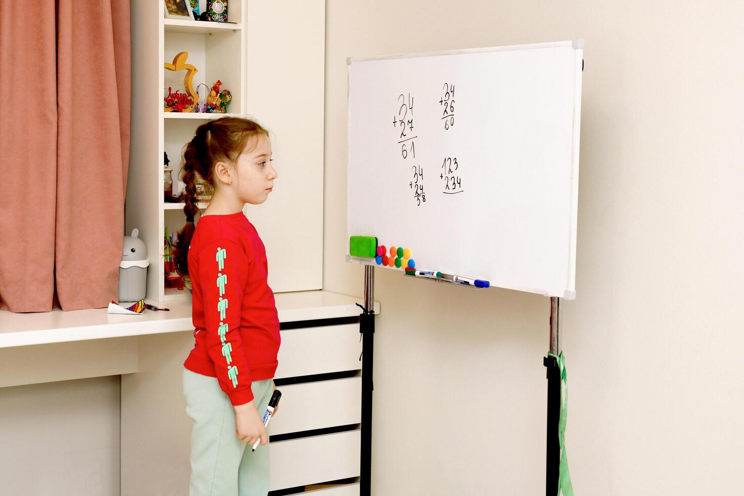 little girl solves house examples on the blackboard photo