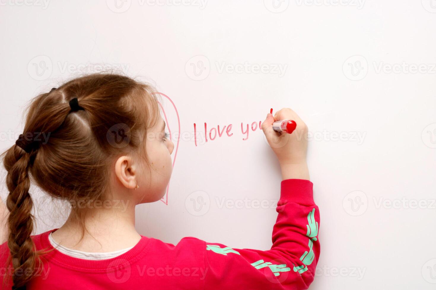 little girl writes I love you on a white board with a red marker photo