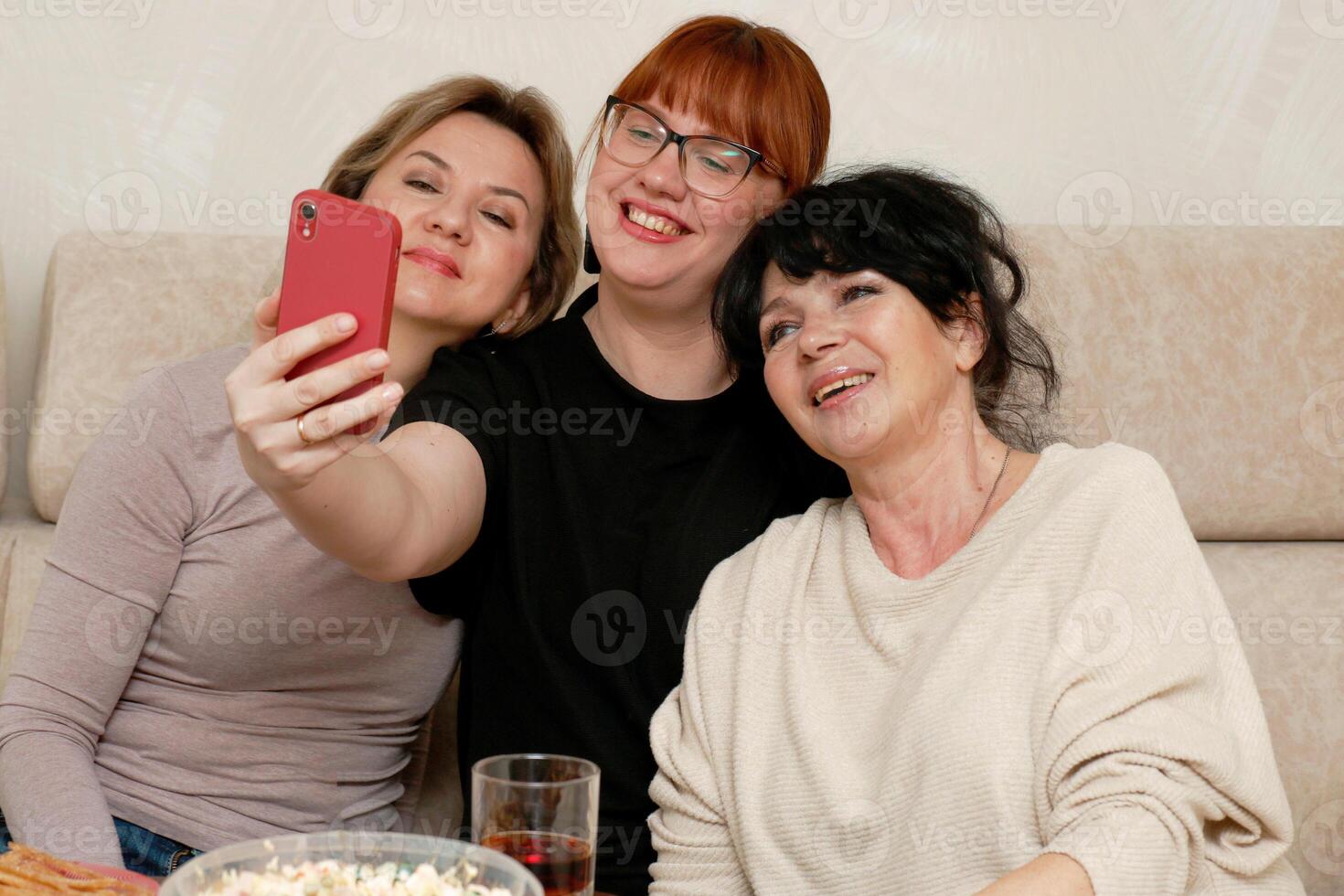 Tres riendo mujer tomando un selfie a el teléfono foto