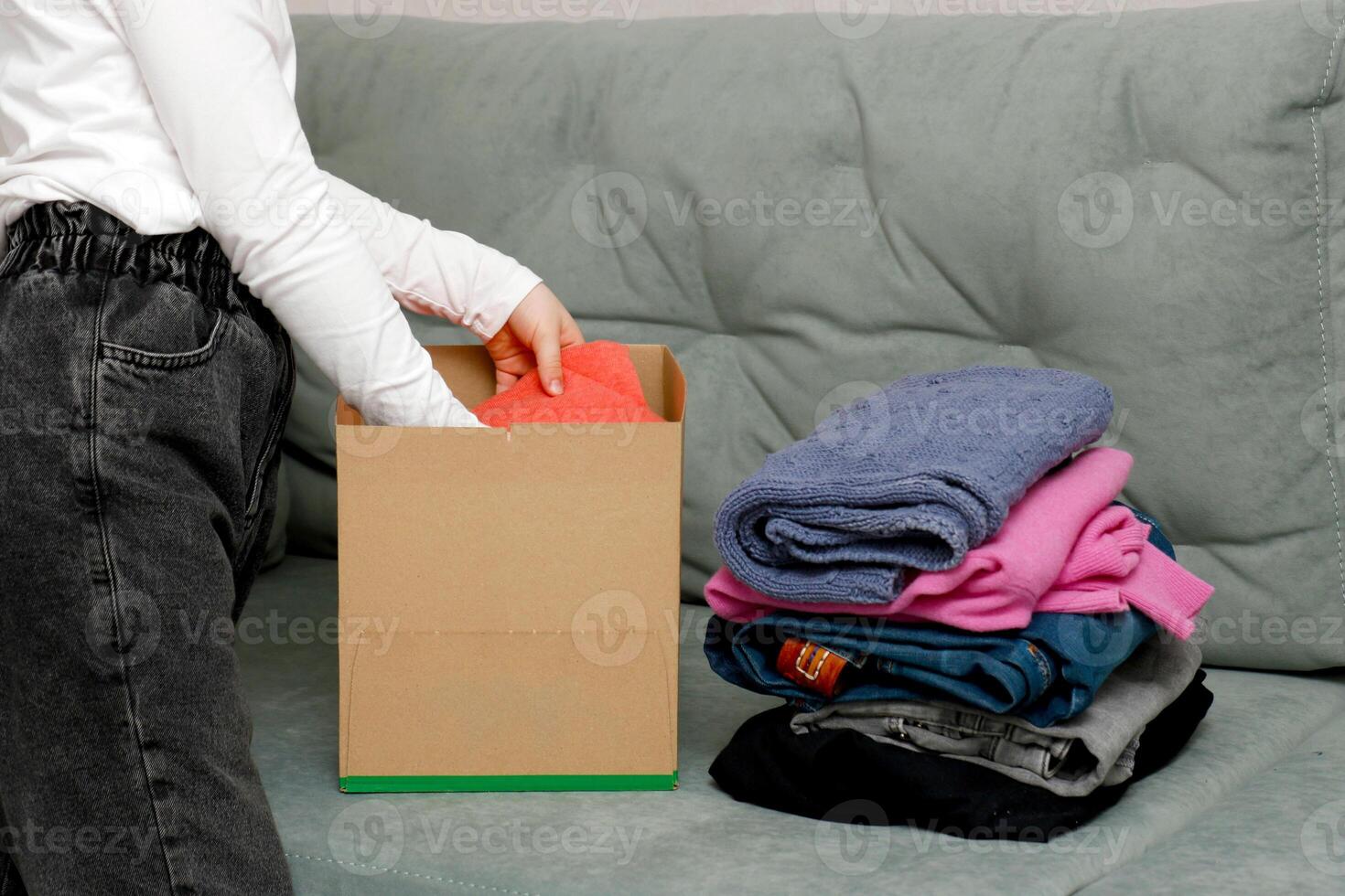 niña con coletas plegable ropa para donación en un caja foto