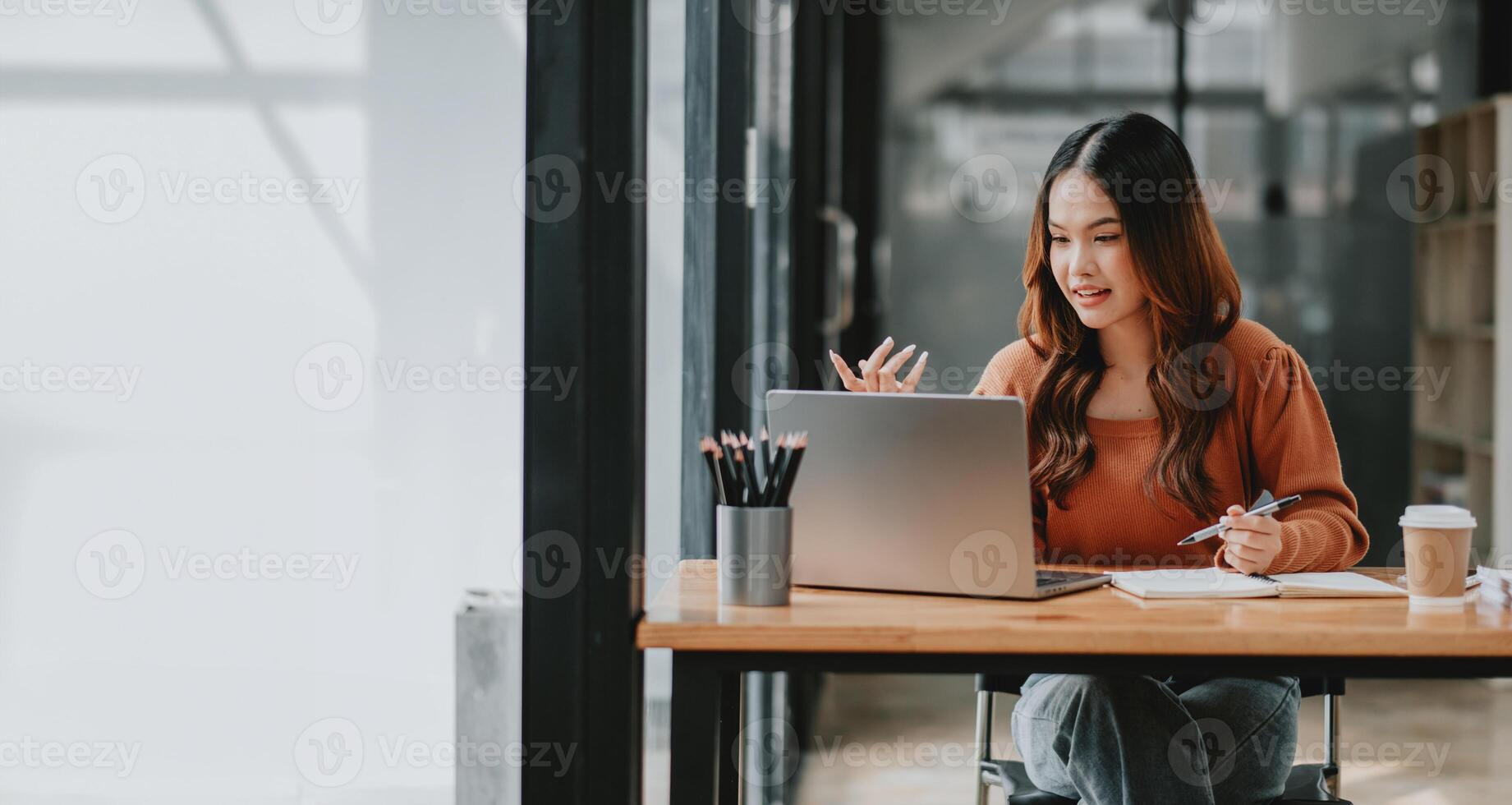Young businesswoman looks animated and engaged while speaking during a conference call on her laptop in a stylish workspace. photo