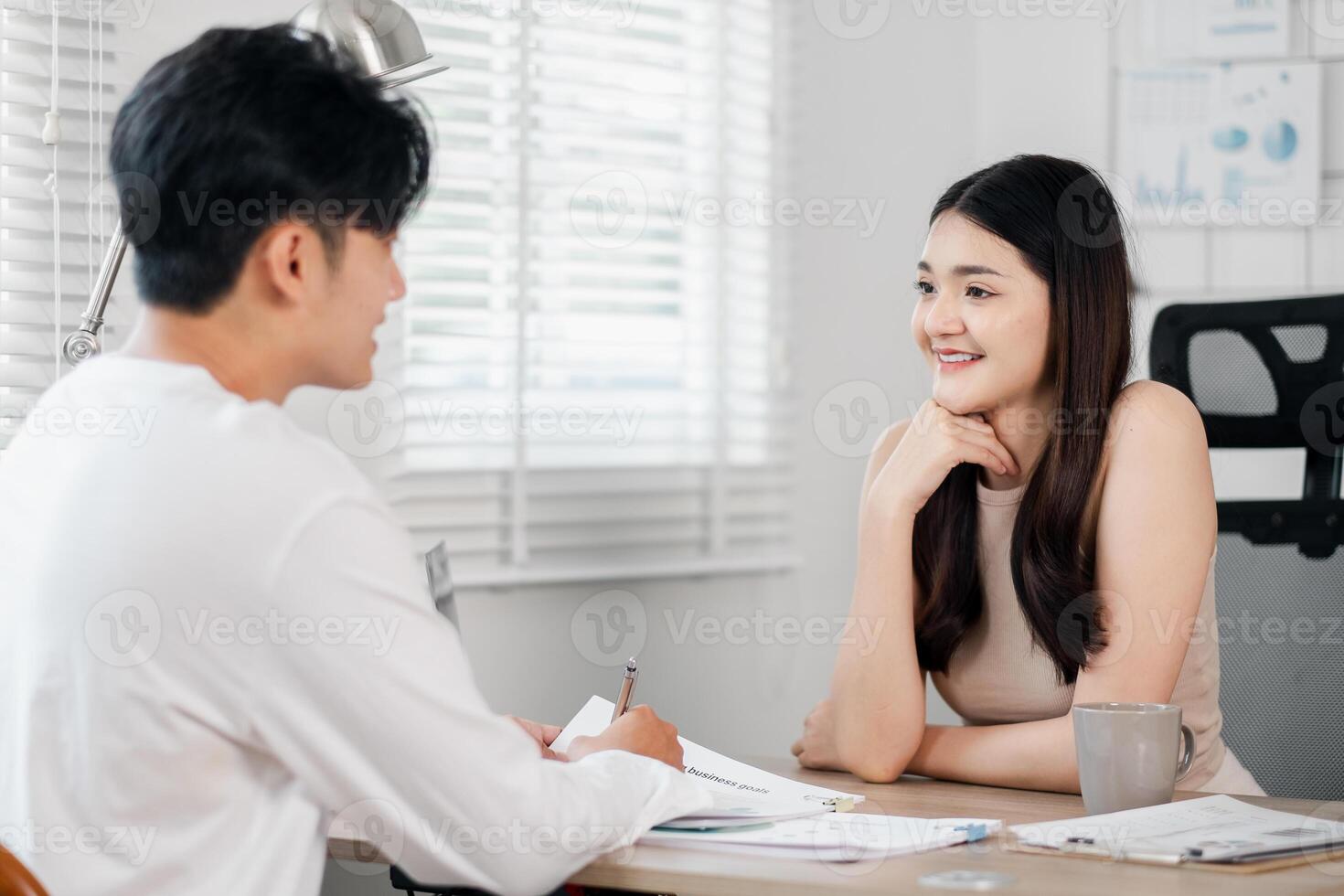 Young woman attentively listens while a man takes notes, both deeply involved in a home office discussion. photo