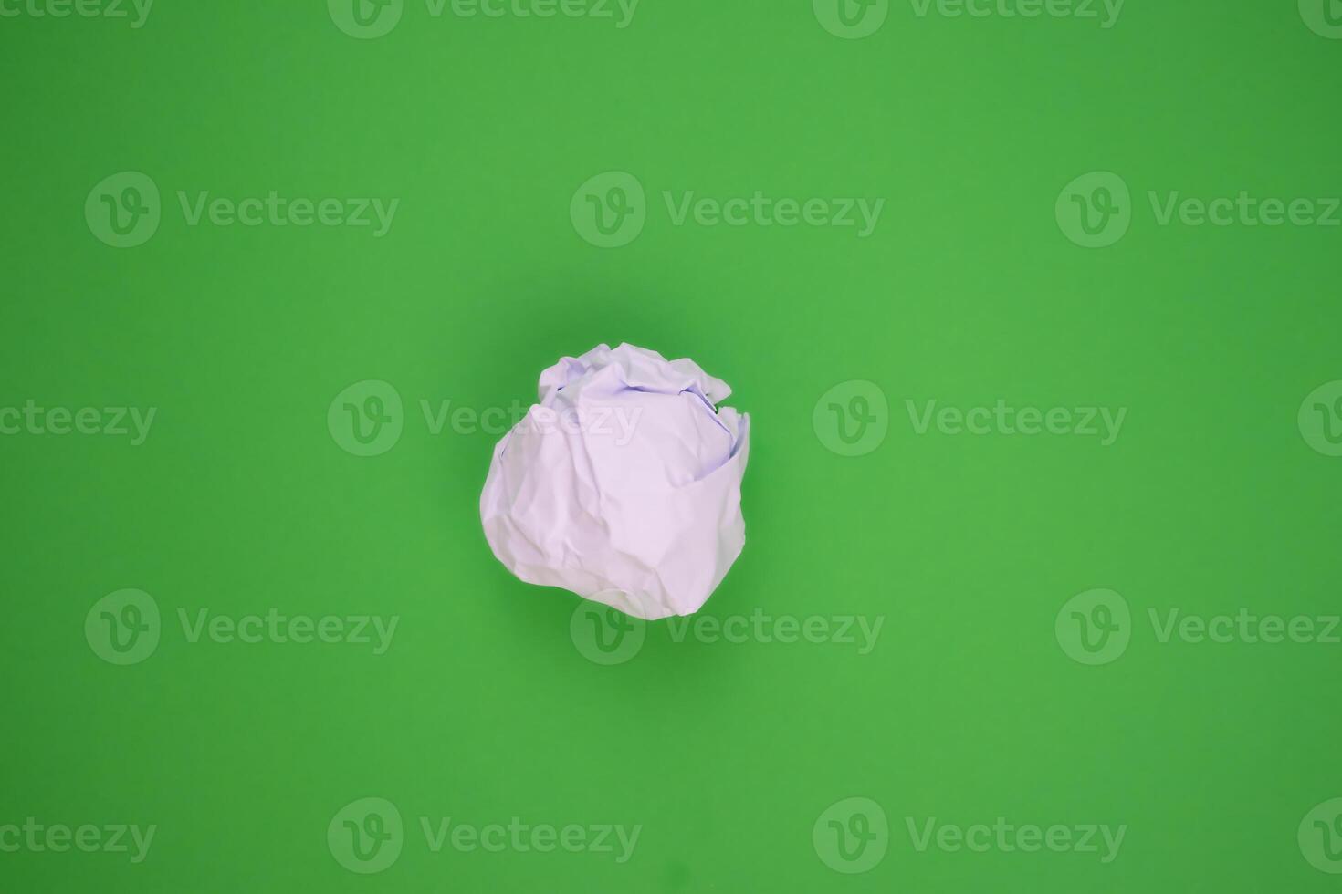 White crumpled paper on a green background. Recycling concept. photo