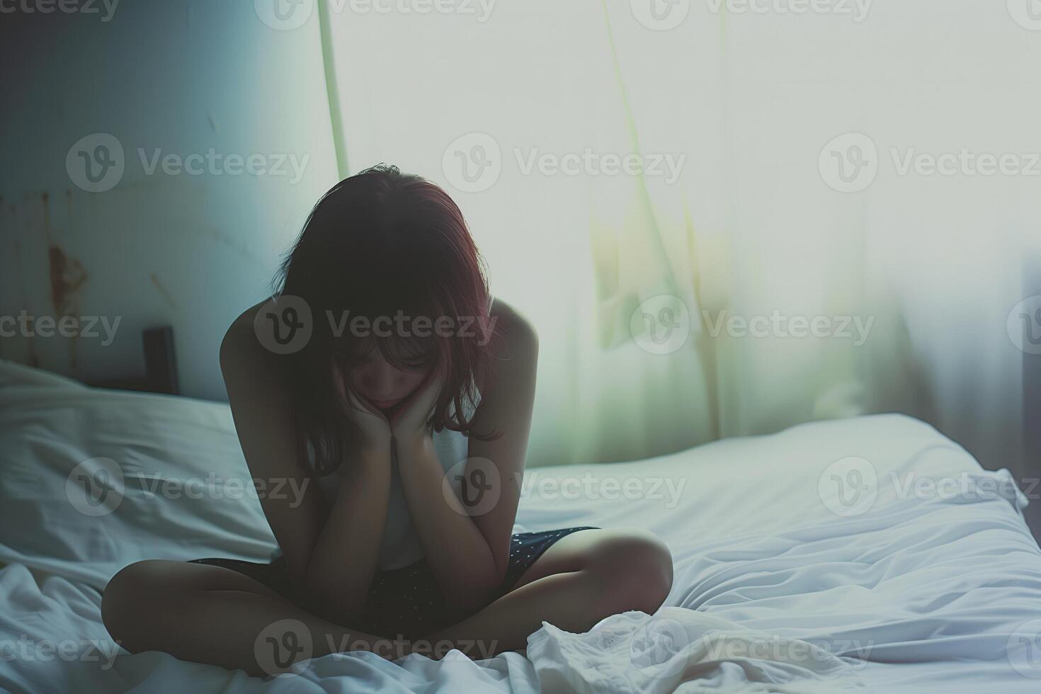Asian girl feeling sad and lonely in the bedroom under dim light photo