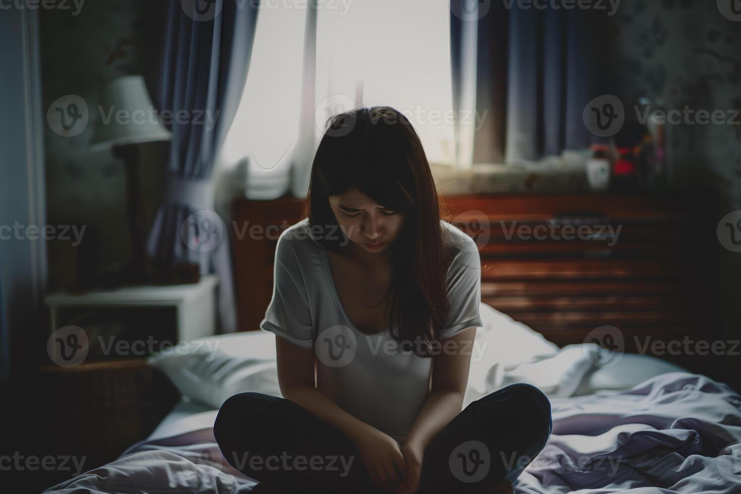 Asian girl feeling sad and lonely in the bedroom under dim light photo