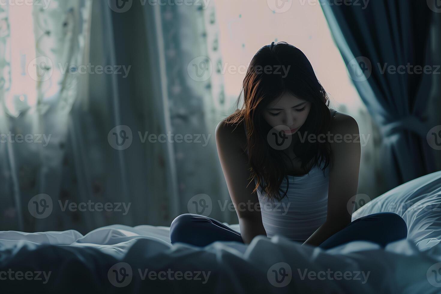 Asian girl feeling sad and lonely in the bedroom under dim light photo