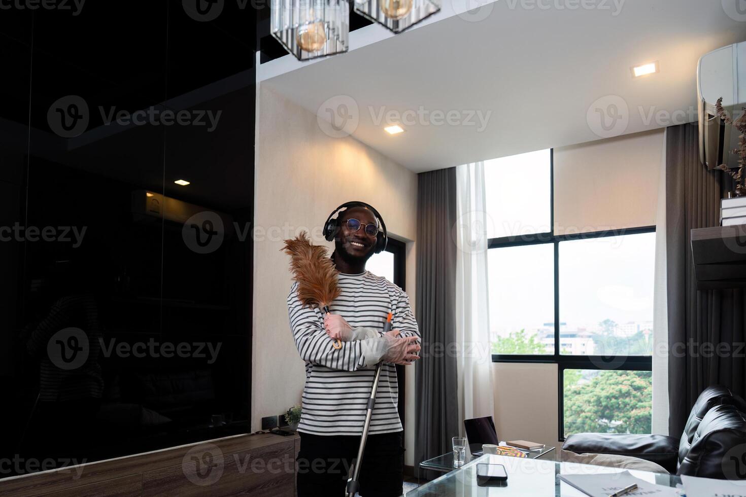 Young African American man for cleaning apartment, holding mop and other cleaning tools. Cheerful african american man housekeeping on weekend photo