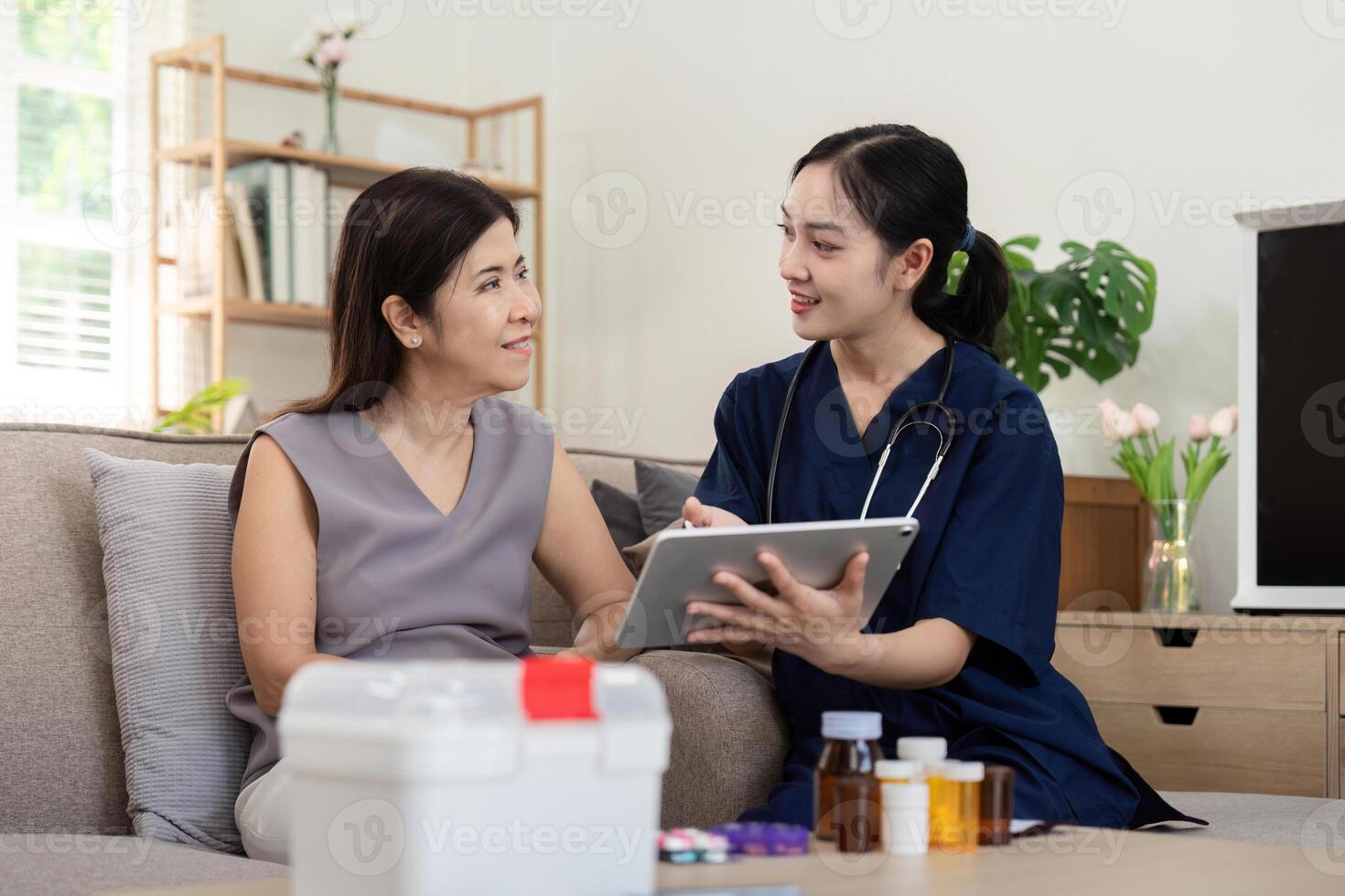 Female caregiver showing medical test result explaining prescription using digital tablet app visit senior woman patient at home sitting on sofa. Elderly people healthcare tech concept photo