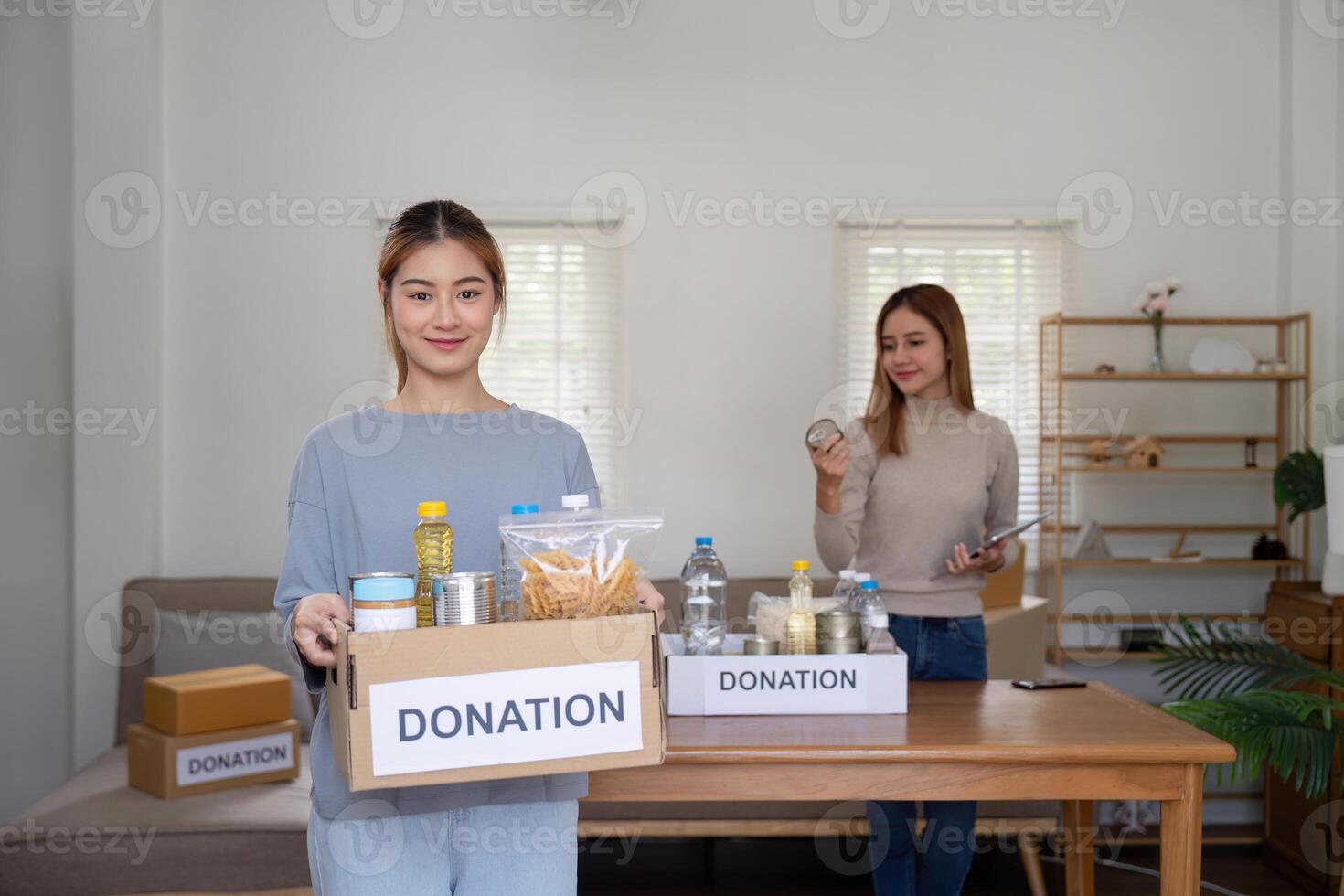 Donation and two woman volunteer asian of happy packing food in box at home. Charity photo