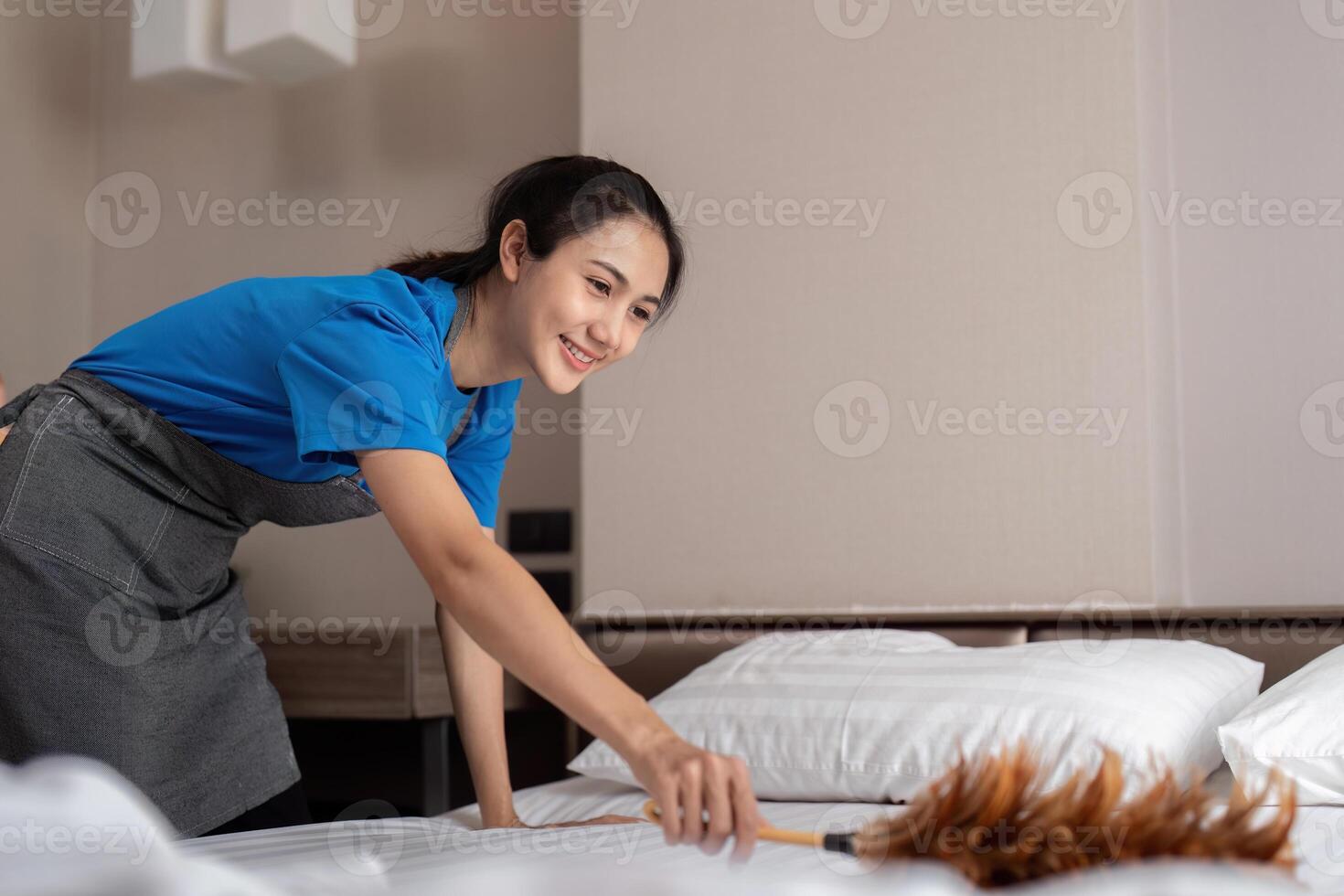 A woman asian staff cleaning service, tool and bucket for work. a young female cleaner with products to clean a bedroom, Dust off the bed photo