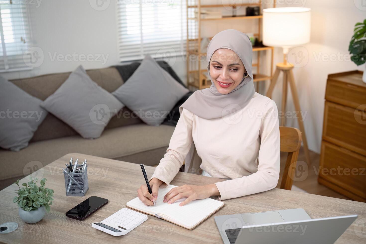 Young muslim business woman calculate budget money finance. Muslim woman accountant use calculator typing laptop counting tax loan bills online payment write document paperwork at home office photo