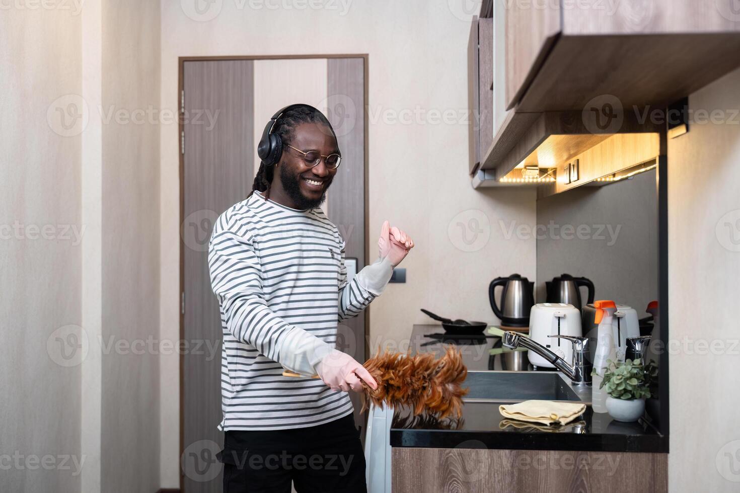 African American man listening to music while cleaning in kitchen photo