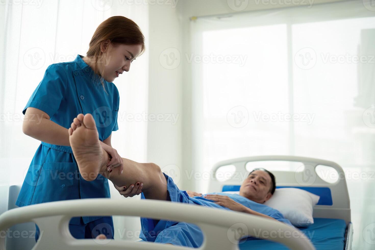 Physical therapist Asian woman, doing leg physiotherapy for elderly man to treat osteoarthritis and nerve pain in the leg to nursing at home and health care concept photo