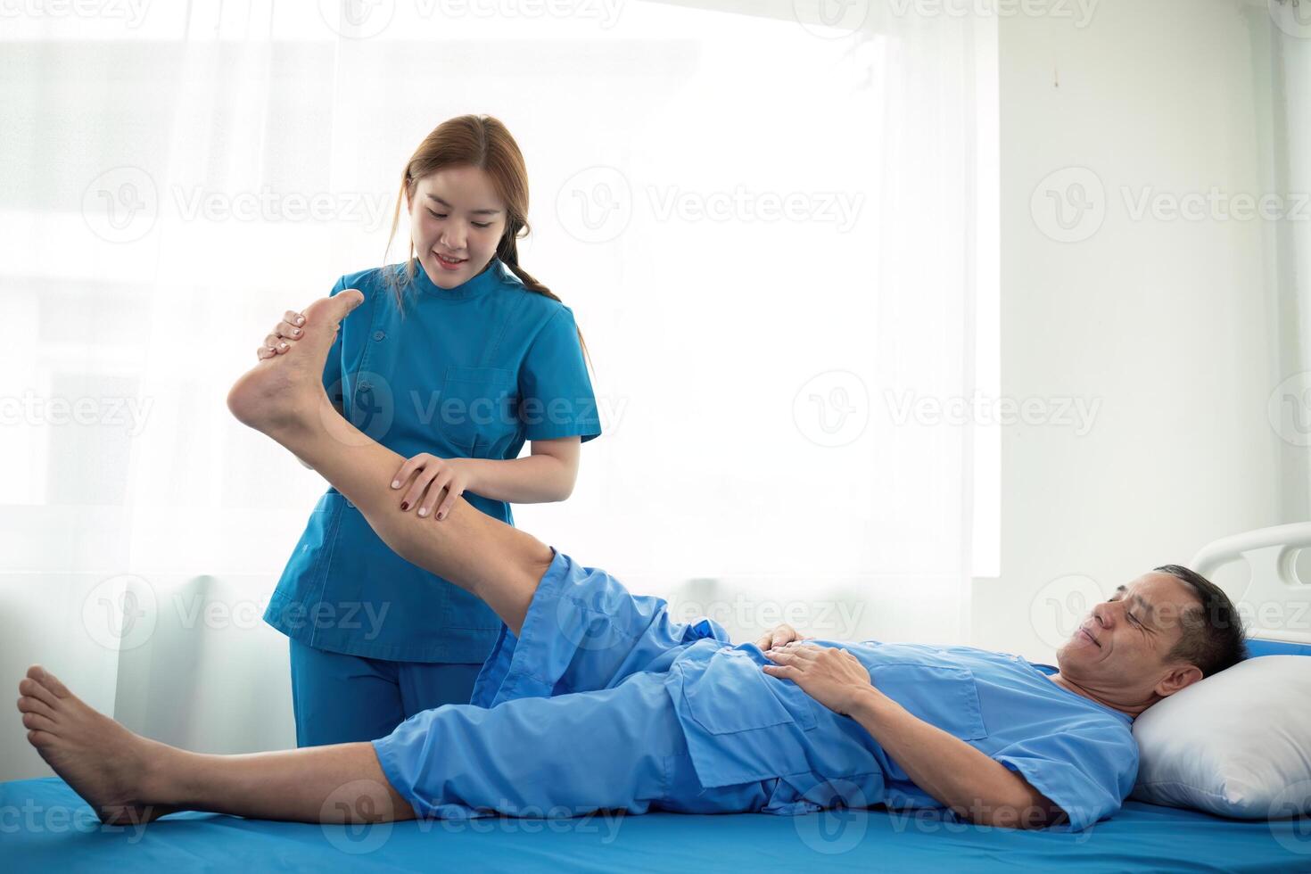 Physical therapist Asian woman, doing leg physiotherapy for elderly man to treat osteoarthritis and nerve pain in the leg to nursing at home and health care concept photo