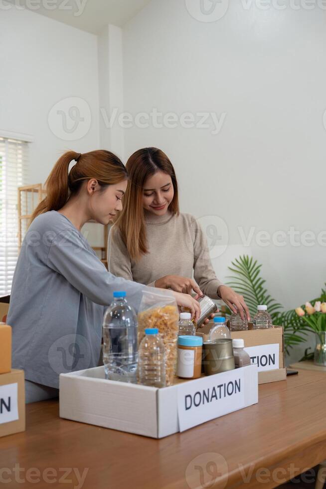 Donation and two woman volunteer asian of happy packing food in box at home. Charity photo