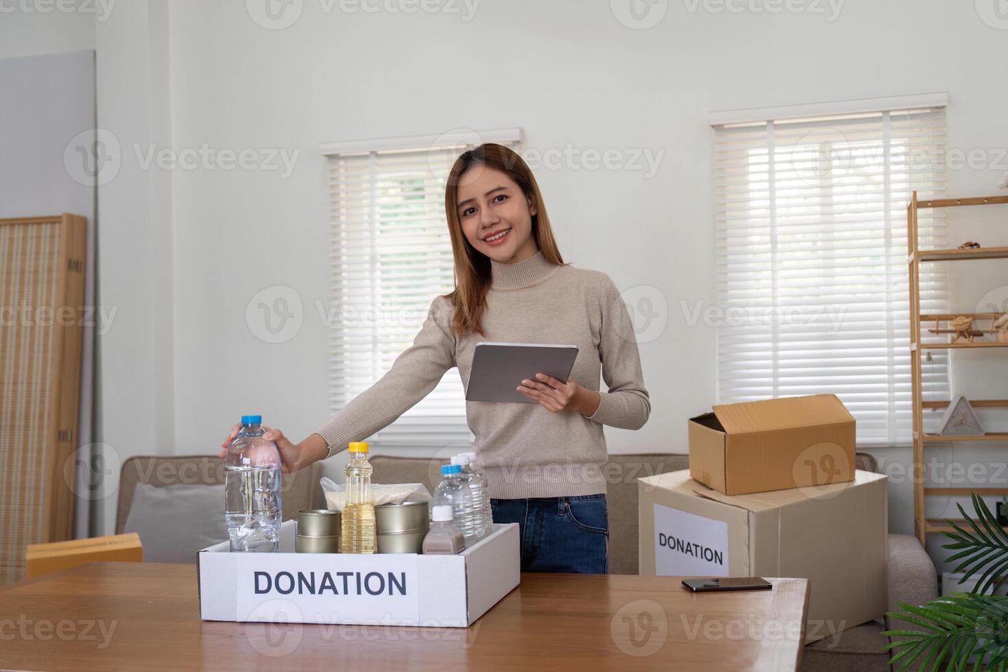 Volunteer woman asian pack donate food in cardboard box for people in need during photo