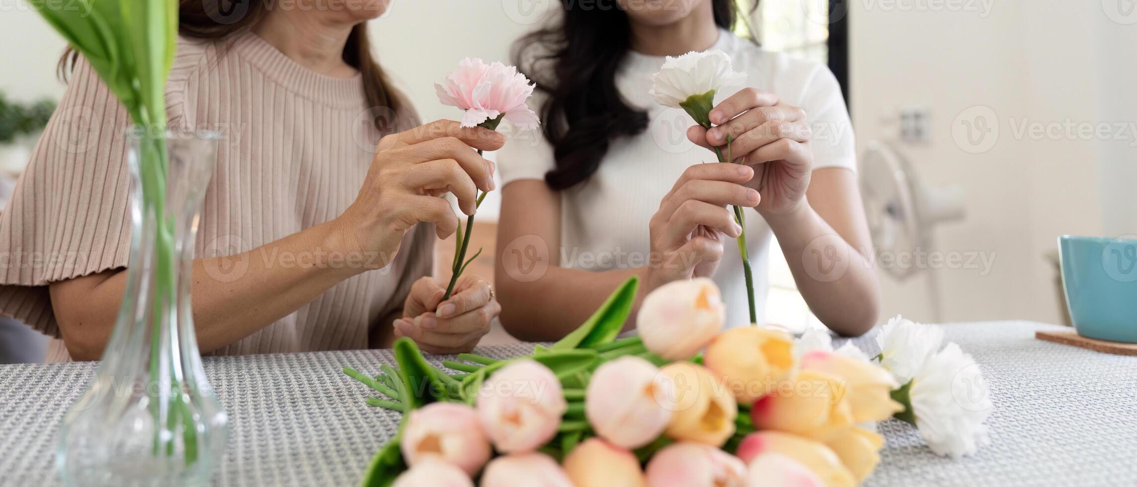 mayor madre y adulto hija contento en el mesa mientras organizar flores en un florero juntos. tecnología y estilo de vida concepto. contento hora juntos foto