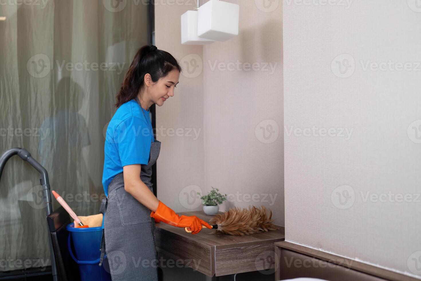 Cleaning service woman worker cleaning in bedroom at apartment. housekeeper cleaner feel happy and use feather duster wiping messy dirty for housekeeping housework or chores photo