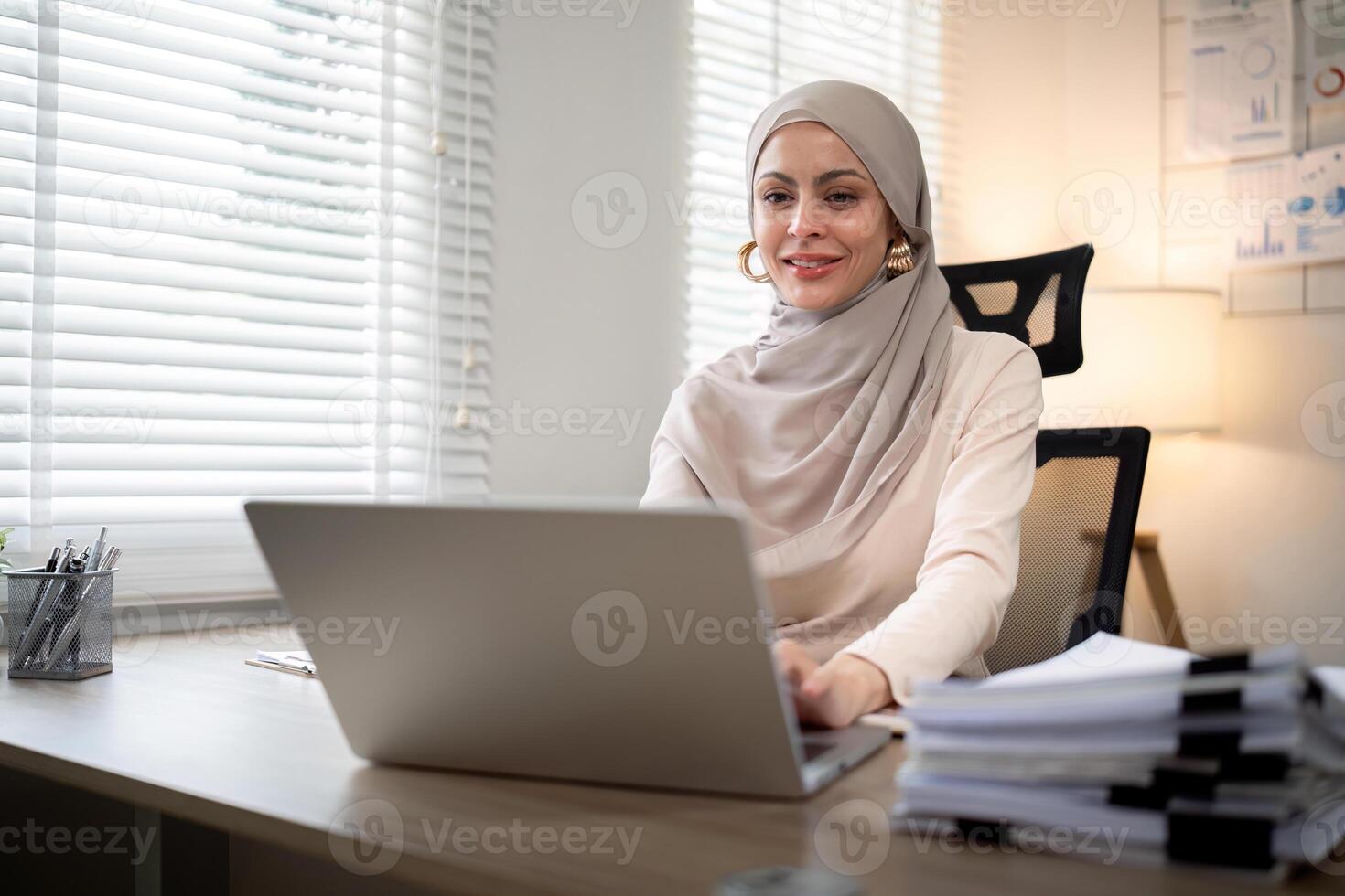 Asian Muslim businesswoman in hijab head scarf working with paper document in the modern office. diversity and office concept photo