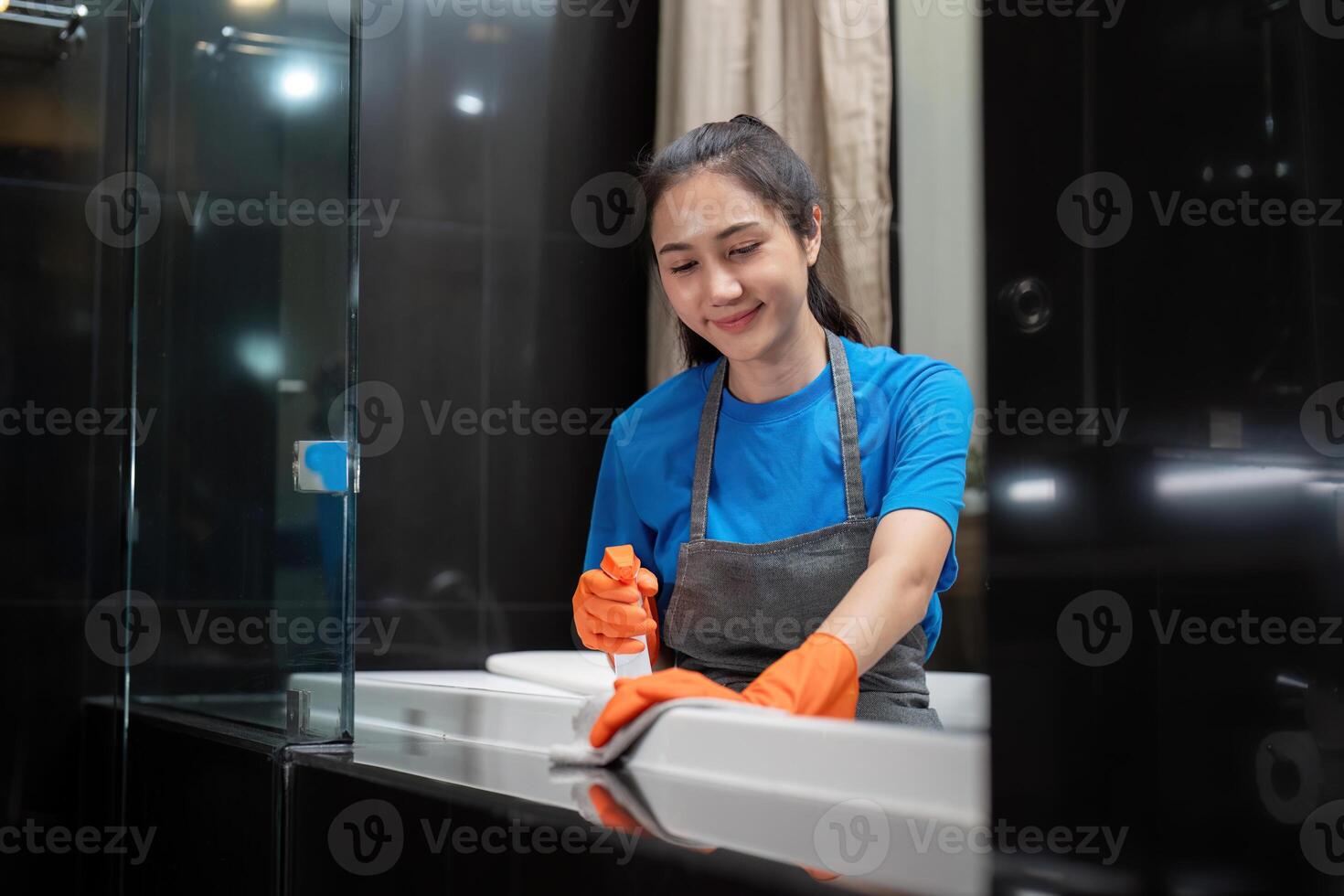 profesional limpieza Servicio empresa empleado en caucho guantes limpieza y detergente rociar en baño foto