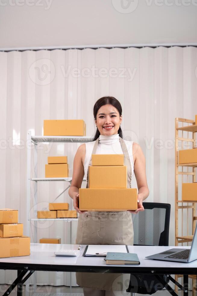 Young business woman asian working online ecommerce shopping at her shop. Young woman sell prepare parcel box of product for deliver to customer. Online selling photo
