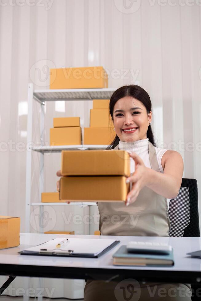 Young business woman asian working online ecommerce shopping at her shop. Young woman sell prepare parcel box of product for deliver to customer. Online selling photo