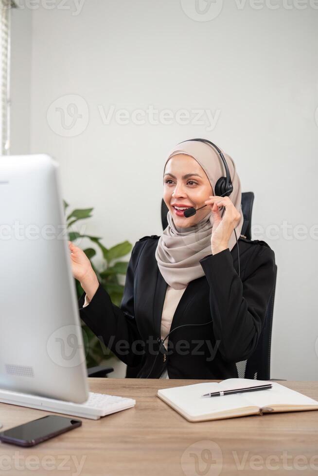 Young muslim women wearing hijab telemarketing or call center agent with headset working on support hotline at office photo