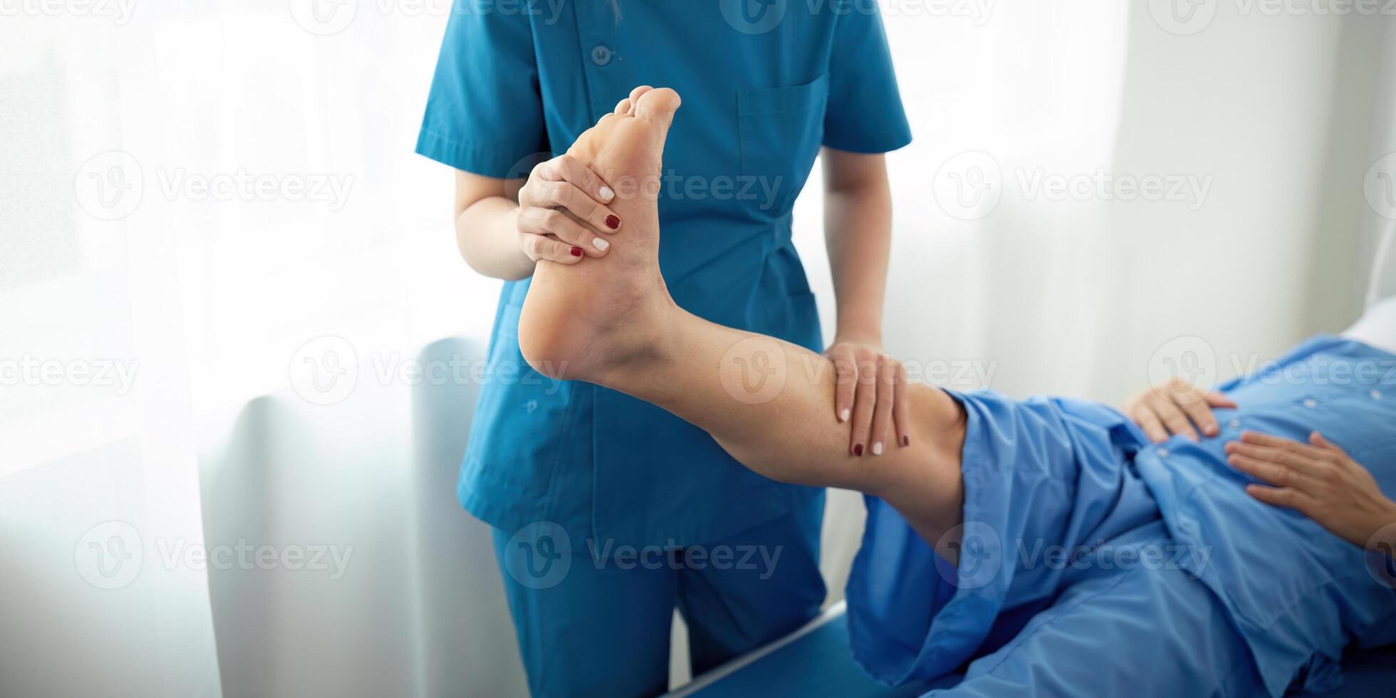 Physical therapist Asian woman, doing leg physiotherapy for elderly man to treat osteoarthritis and nerve pain in the leg to nursing at home and health care concept photo