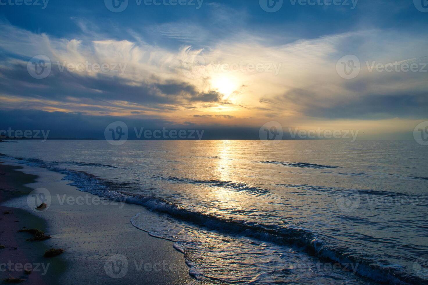 Sunset, illuminated sea. Sandy beach in the foreground. Light waves. Baltic Sea photo