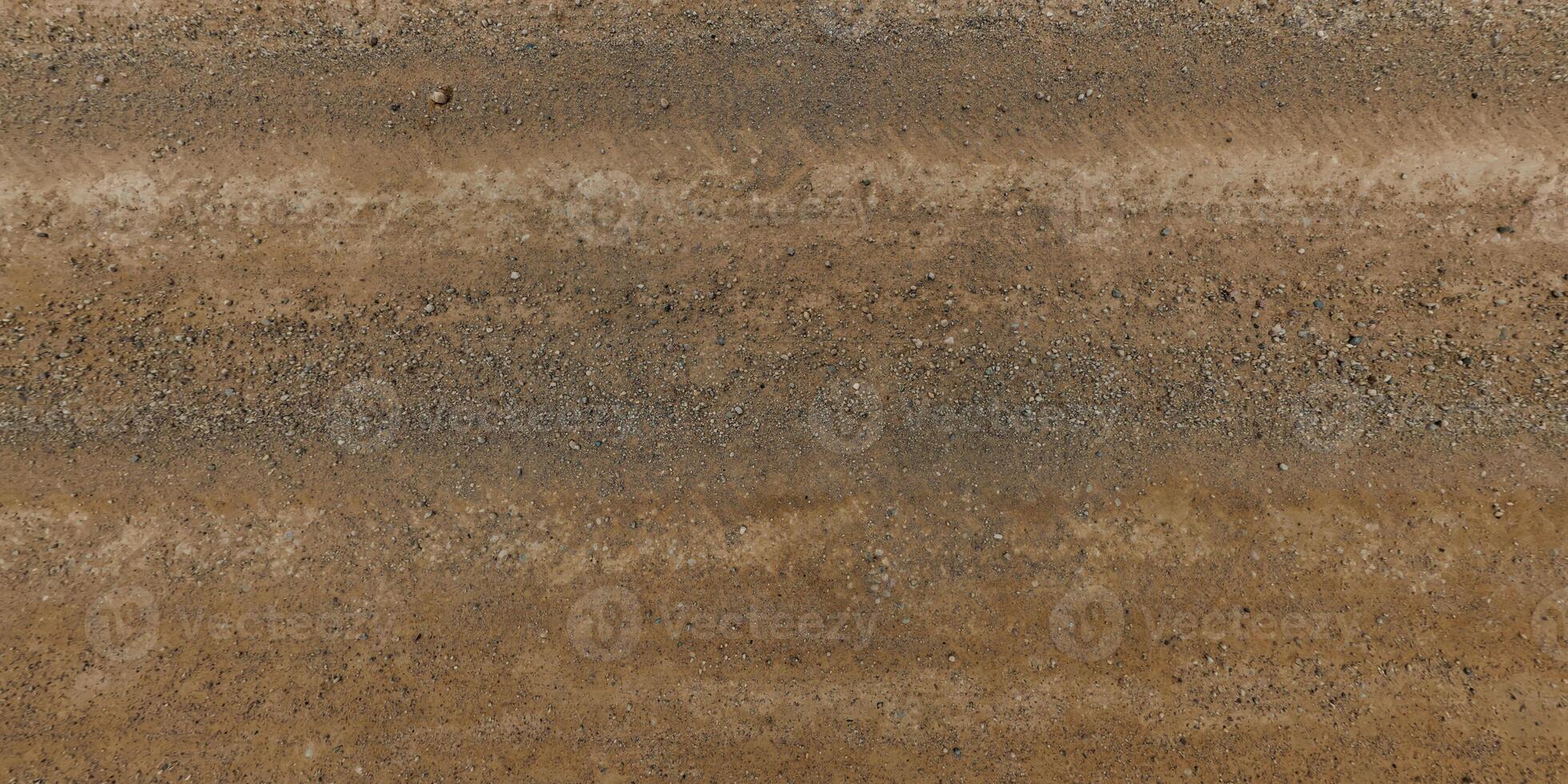 panorama of road from above on surface of gravel road with car tire tracks photo