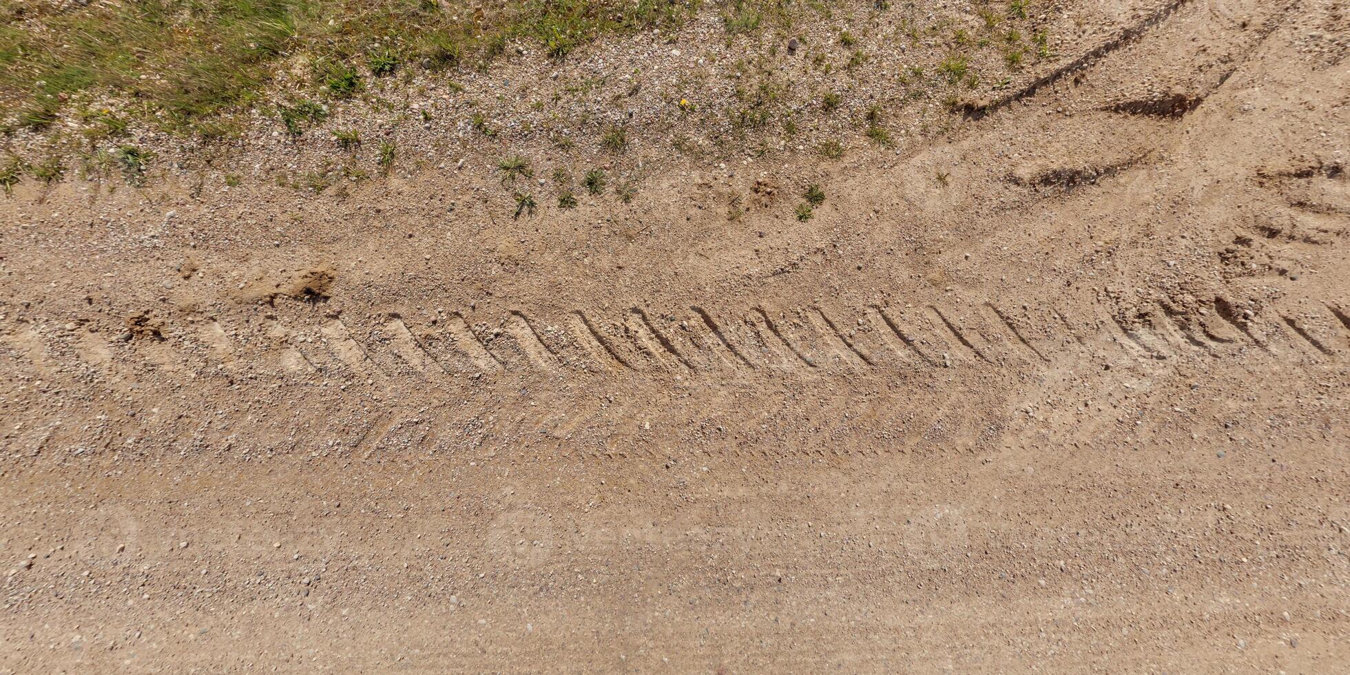panorama of road from above on surface of gravel road with car tire tracks photo