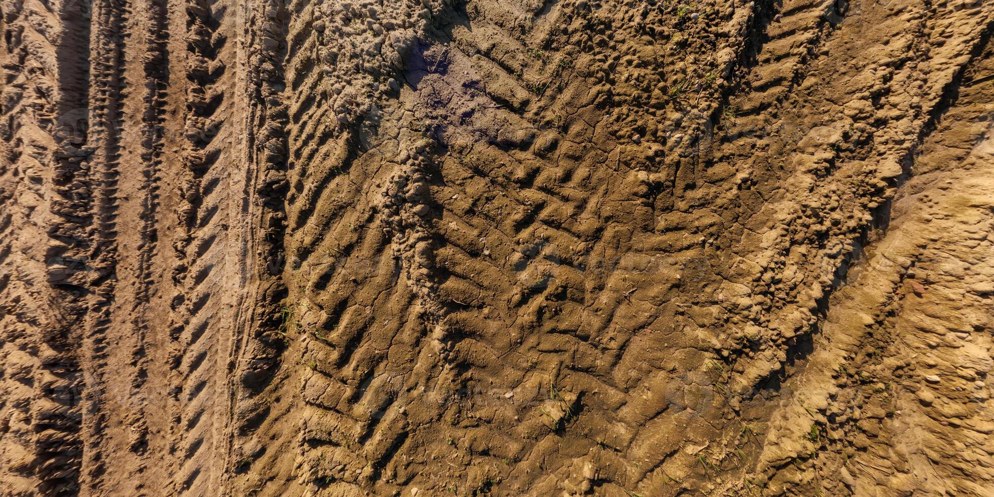 view from above on texture of wet muddy road with tractor tire tracks in countryside photo