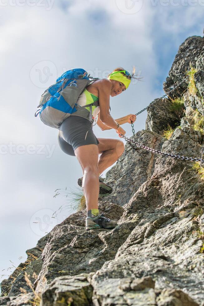 Woman climbs on a chain on an equipped route photo