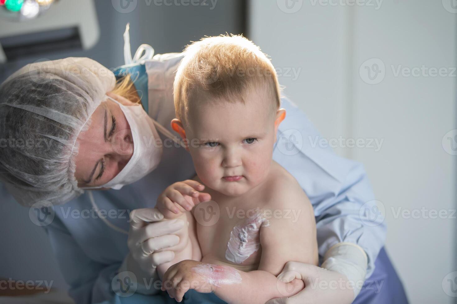 A little boy nurse treats a burn. A child in the hospital is injured. The doctor treats the baby. Little hospital patient. photo