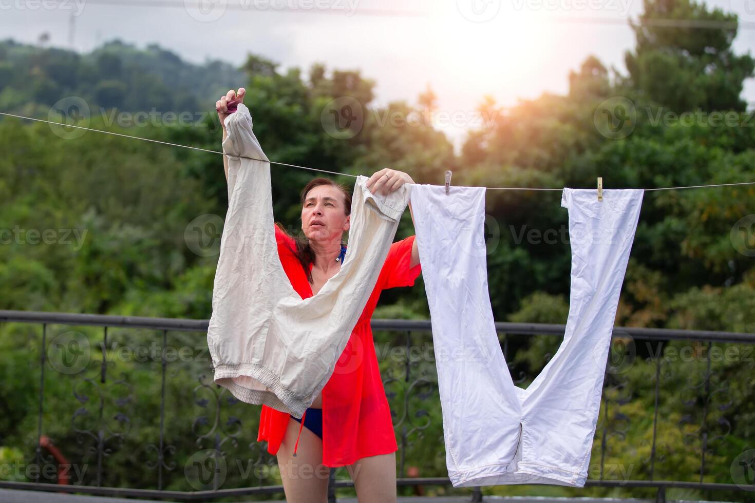 A woman hangs her washed clothes to dry outdoors. photo