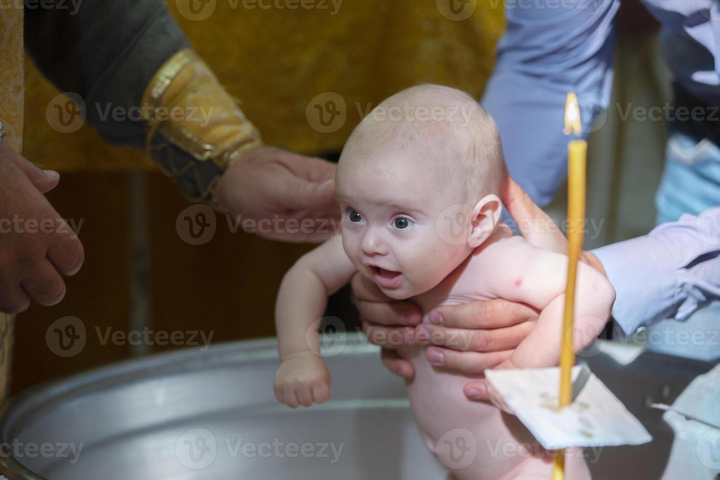 Orthodox baptism of an infant. Bathing a baby in a church font when accepting faith. photo