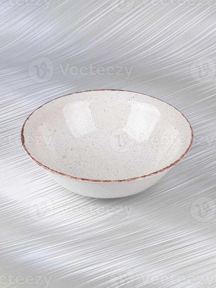 White empty deep clay plate with a spoon on a gray background. photo