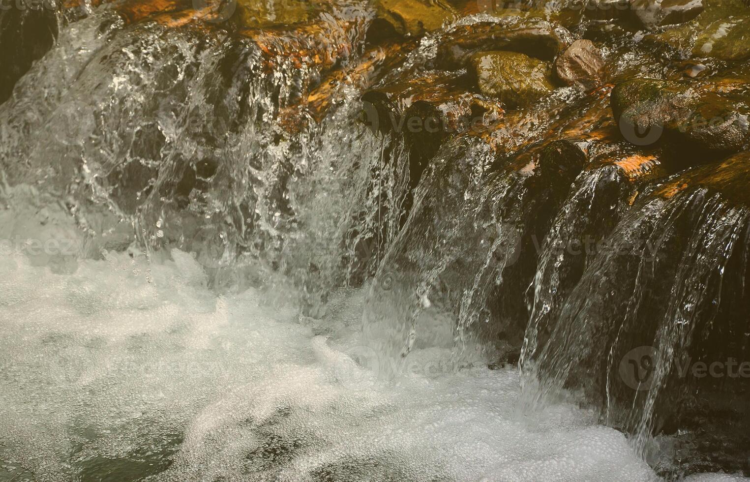 A small waterfall. The height difference of the water flow in the river is equipped with round wooden logs photo