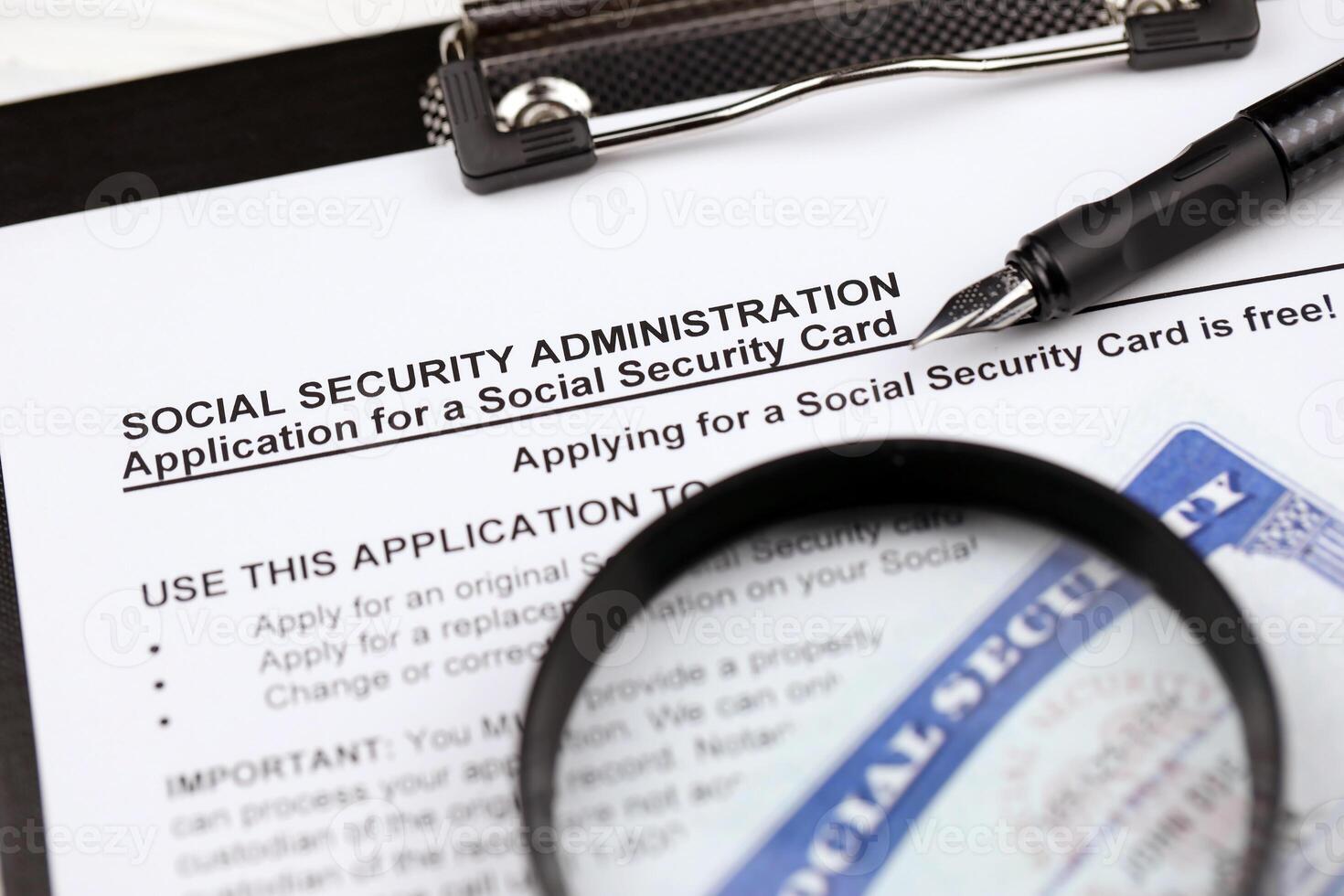 United States social security number cards lies on Application from social security administration on A4 tablet lies on office table with pen and magnifying glass photo