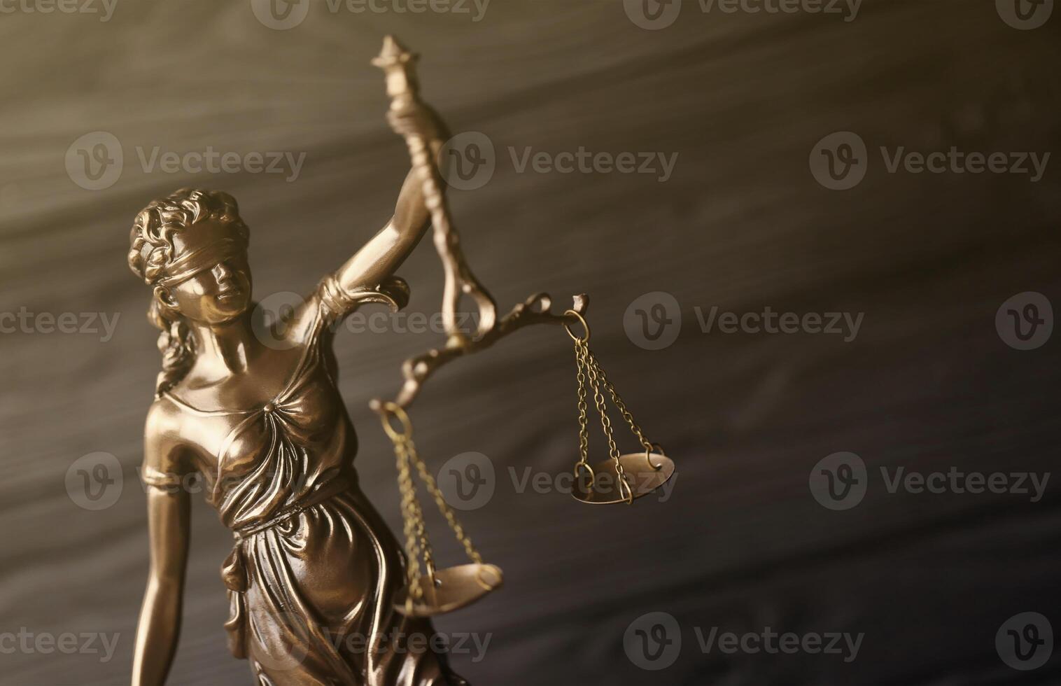 The Statue of Justice - lady justice or justitia the Roman goddess of Justice. Statue on black wooden wall. Concept of judicial trial, courtroom process and lawyers work photo