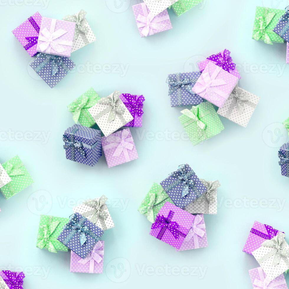 Piles of a small colored gift boxes with ribbons lies on a violet background. Minimalism flat lay top view pattern photo