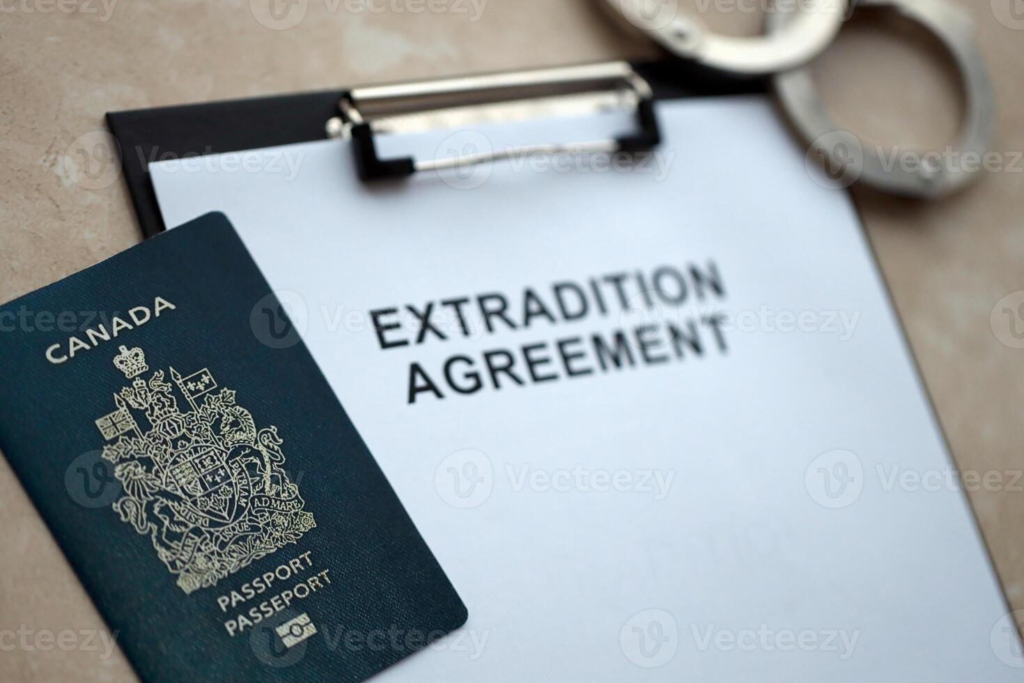 Passport of Canada and Extradition Agreement with handcuffs on table photo