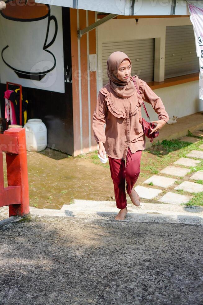 Javanese woman wearing a hijab is walking against the background of sunlight in the park. photo