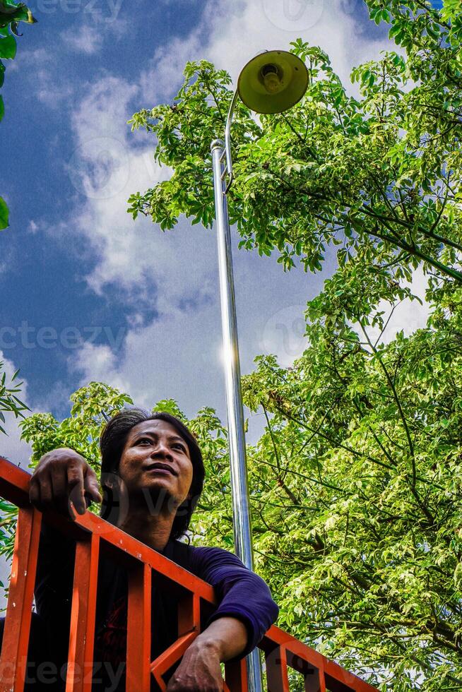 Bottom view of a man sitting in the garden with his gaze straight at the background of the trees. photo