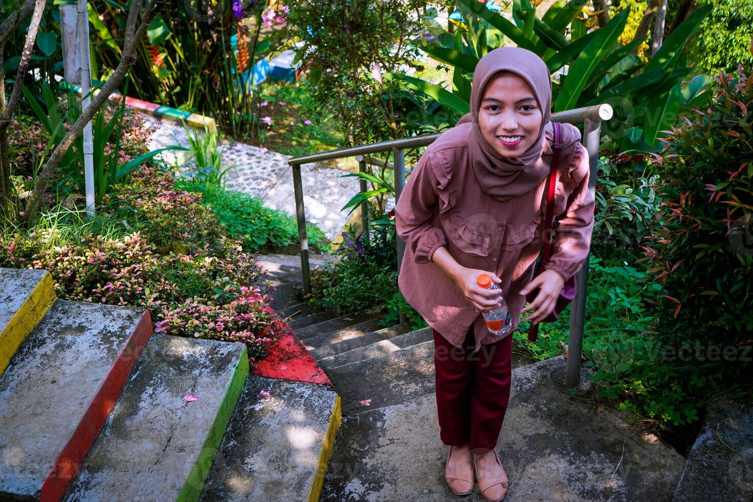 top view of a woman in a headscarf walking on the park steps facing the camera. photo