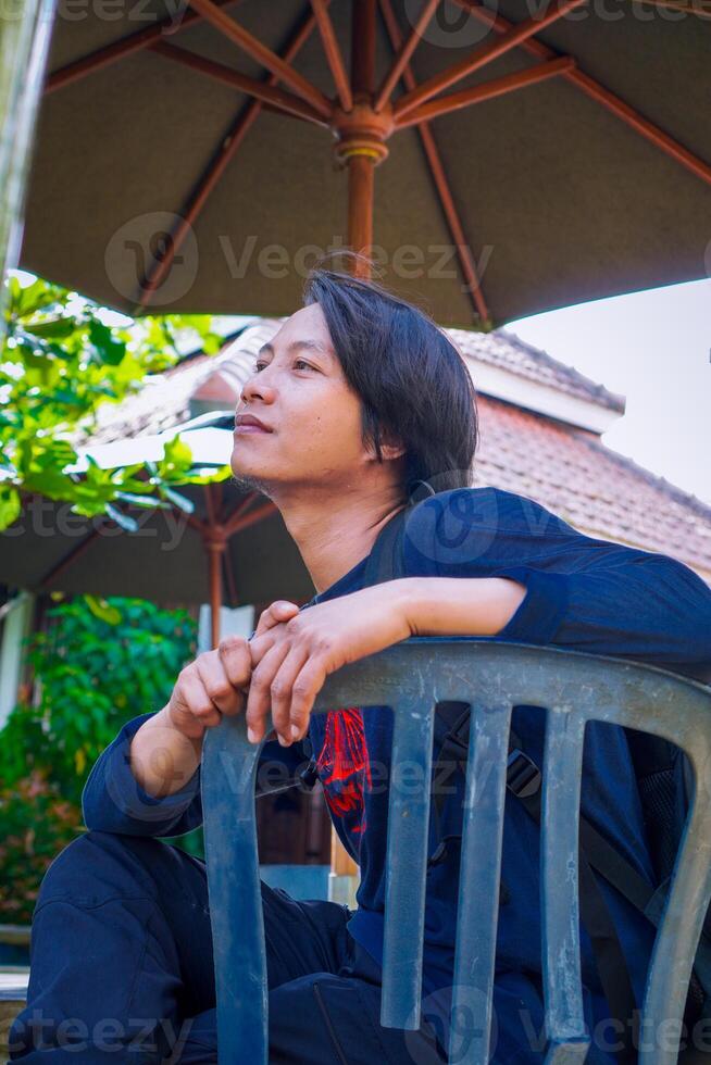 Javanese man sitting pensively in the garden with a background of green plants. photo